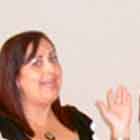 Nesta foto em cores, uma mulher fala ao microfone que um homem segura, como se fosse um repórter. Nota-se que ela gesticula ao falar e olha para a câmera. Ao lado dela, há outra mulher que deixa escapar discreto sorriso. O repórter tem feição séria e olha para outra direção que não a entrevistada. Atrás deles, percebe-se um banner com o desenho de dois corações sorridentes dentro de uma camisinha.