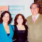 Duas mulheres e um homem aparecem nesta foto lado a lado, posando para a câmera e sorrindo. Ao fundo, notam-se painéis formados por cartuns coloridos.