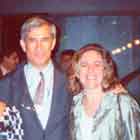 Esta foto em cores revela grupo de sete mulheres e um homem em pé, lado a lado. Percebe-se que, com exceção da mulher à direita, todos posam para a câmera. Ao fundo, notam-se outras pessoas circulando pela mostra.