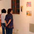 Esta foto em cores mostra pessoas à esquerda olhando cartuns afixados na parede.