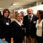 Esta foto em cores revela grupo de três mulheres e um homem em pé, lado a lado. Percebe-se que, com exceção da mulher à direita, todos posam para a câmera. Ao fundo, notam-se outras pessoas circulando pela mostra.