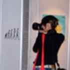 Nesta foto em cores, um grupo de pessoas conversa em frente a um dos painéis. À esquerda, percebe-se que uma mulher fotografa alguns cartuns expostos.