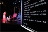 Not�cia: Teatro acess�vel pelo Brasil come�a em agosto com patroc�nio Vale. Descri��o da imagem: a fotografia mostra um palco de teatro equipado com um grande tela em que se projeta a legenda eletr�nica da cena. No palco dialogam os personagens �ngelo e Janu�ria. Ela est� em p�, enquanto o homem aparece no ch�o do palco. O fundo do cen�rio � preto, destacando os elementos cenogr�ficos, que s�o cadeiras que se parecem com assentos de cinema. A primeira das cadeira tem forro vermelho; as demais, parecem em couro preto. Tamb�m se veem em cena grandes estruturas tubulares que formam cubos, mas n�o � poss�vel descobrir a finalidade destes objetos c�nicos. Os personagens est�o iluminados por luzes coloridas, oriundas dos refletores azuis e amarelos no teto do palco. Em primeiro plano, entretanto, n�o est� o palco, mas a tela que projeta a legenda eletr�nica, um dos formatos acess�veis oferecidos em todos os espet�culos teatrais do grupo �Os Inclusos e os Sisos�. A legenda reproduz em letras brancas sobre fundo preto o di�logo entre Janu�ria e �ngelo, a seguir descrito. Janu�ria: Eu? Eu sou escritora... trabalho em casa... n�o entendo absolutamente nada dessas coisas. �ngelo: T� de sacanagem? Fica o dia inteiro na internet e n�o aprendeu a fazer uma liga��o direta? Janu�ria: Eu n�o fico o dia inteiro na internet! �ngelo: Sei... Janu�ria: Eu fico um pouco... Fim da descri��o.