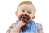 Not�cia: �A ci�ncia do prazer: por que gostamos do que gostamos?�. Descri��o da imagem: retrato de um beb� lambuzando-se de chocolate. A crian�a branca de cabelo loiro penteado para o lado parece um menino de aproximadamente um ano de idade. Ele usa uma blusa com listras coloridas e um babador azul. Com a m�o esquerda ele segura um peda�o de bolo de chocolate enquanto, com a outra, leva o doce � boca. Suas bochechas e seu nariz est�o completamente lambuzados, bem como seus dedinhos e parte do bra�o, al�m, claro, do babador. O fotografado est� sorrindo, o que permite notar dentes superiores e inferiores em forma��o. Fim da descri��o.