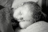 Descri��o da imagem: fotografia em preto-e-branco onde se v� uma menina, de aproximadamente cinco anos de idade, com a cabe�a recostada sobre seu bra�o, deitada em uma almofada, de olhos fechados, coberta at� o pesco�o por uma manta. Fim da descri��o.