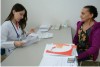 Notcia: Nova poltica amplia financiamento na Ateno Bsica Descrio da imagem: Foto de um consultrio mdico. A mdica, vestindo jaleco branco e com um estetoscpio pendurado no pescoo, est sentada em uma mesa observando um papel para uma paciente. A mdica  jovem, tem pele clara e cabelos compridos e lisos castanhos. A paciente, uma mulher idosa com cabelos pretos presos em um coque na nuca, que veste um casaco roxo por cima de uma roupa estampada em tons florais, est sentada de frente para a mdica. Fim da descrio.
