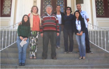 A imagem mostra sete pessoas que estavam reunidas em uma reuni�o sobre acessibilidade para pessoas com defici�ncia visual. Elas est�o de p� em uma escadaria e sorriem enquanto posam para uma foto. Grades brancas de aproximadamente um metro, com hastes finas e verticais, adornam as laterais dos degraus de m�rmore acinzentado. Ao fundo, h� um casar�o dos anos 20 em estilo ecl�tico na cor amarelo-claro, com uma porta principal e duas janelas laterais de madeira com grades. Da esquerda para a direita, posam para a foto: Ana Aparecida Ramos, Designer do CCMS; Jussara Valladares, Coordenadora do CCMS; Professor Ant�nio Borges, criador do sistema de acessibilidade DOSVOX e Professor de Tecnologia Assistiva da P�s-Gradua��o no Instituto T�rcio Pacitti de Aplica��es e Pesquisas Computacionais da UFRJ; Nat�lia Biancovilli, funcion�ria do CCMS; Eug�nia Calazans, Coordenadora-Geral de Documenta��o e Informa��o do Minist�rio da Sa�de; Bruna Hiraici, Coordenadora de Gest�o Documental e Informa��o do Minist�rio da Sa�de; Rodrigo Veras, Administrador. Fim da descri��o.
