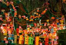 Foto revela maquete na qual se reconhece fração de uma comunidade ou favela que cresceu sobre um morro. As pequenas casas coloridas e prédios foram erguidos sem planejamento, ocupando os contornos do monte. Notam-se muitos fios, também desordenados, representando as ligações caseiras que levam energia elétrica às moradias.