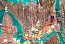 Esta foto mostra um tipo de maquete de uma comunidade ou favela que cresceu sobre um morro. Notam-se as grandes rochas e as pequenas casas coloridas erguidas sem planejamento, ocupando os contornos do monte. Notam-se muitos fios, também desordenados, representando as ligações caseiras que levam energia elétrica às moradias.